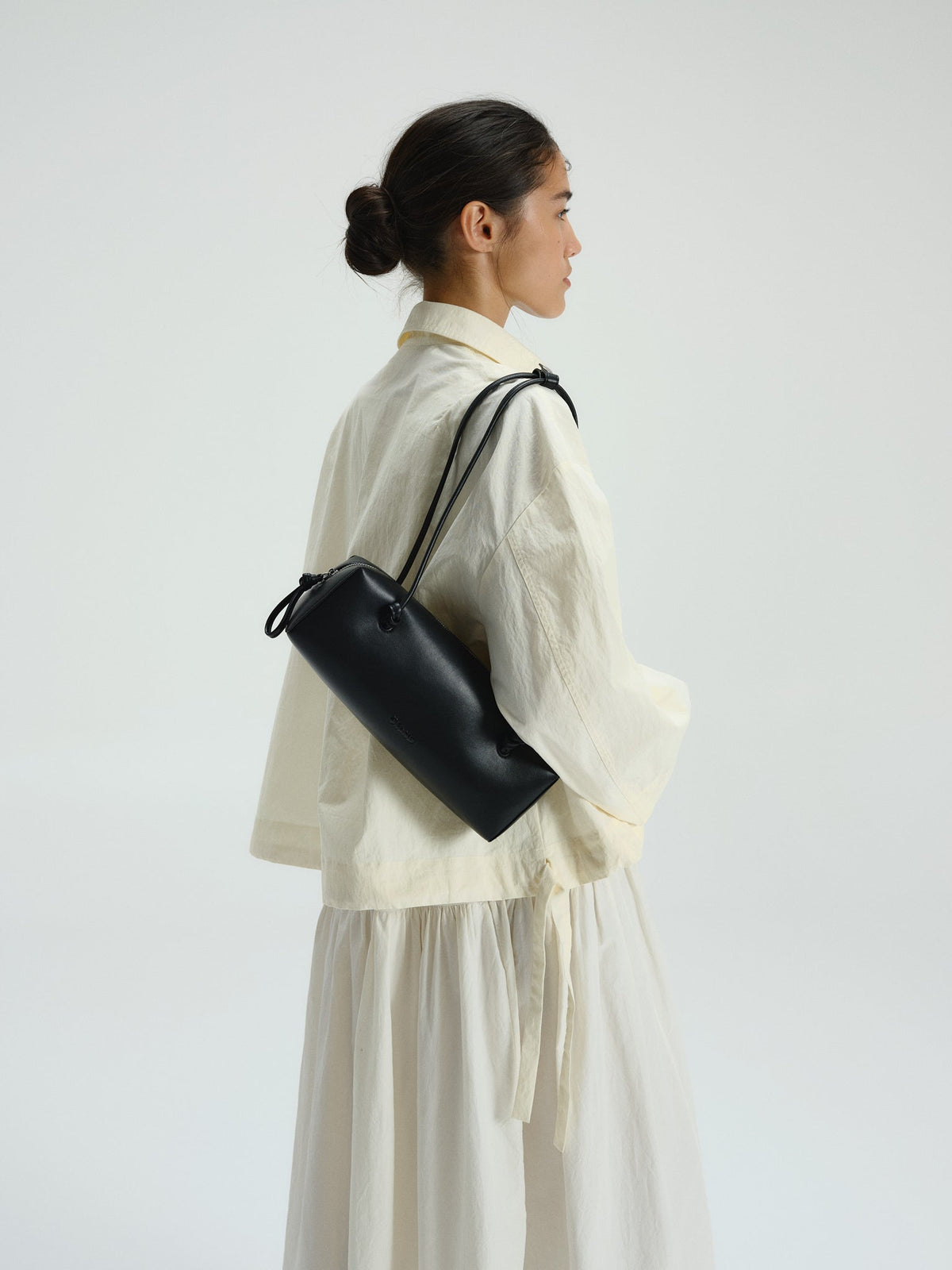 Sac à bandoulière compact en cuir végétalien de qualité supérieure, longues anses nouées, fermeture zippée