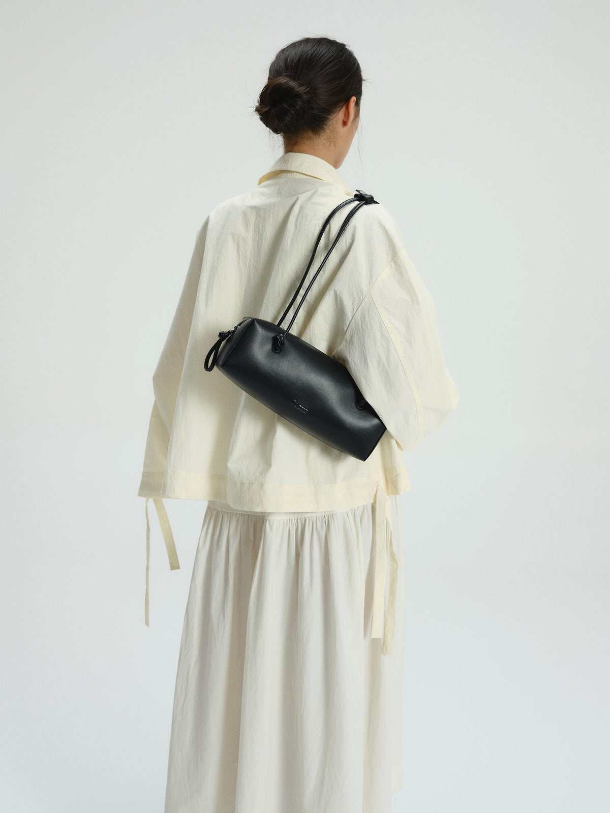 Sac à bandoulière compact en cuir végétalien de qualité supérieure, longues anses nouées, fermeture zippée